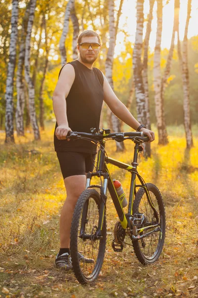 Bisikletli adam orman yolunda gidiyor.