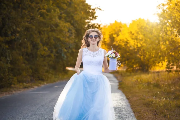 快乐的新娘拿着花束走在绿色的公园里 — 图库照片