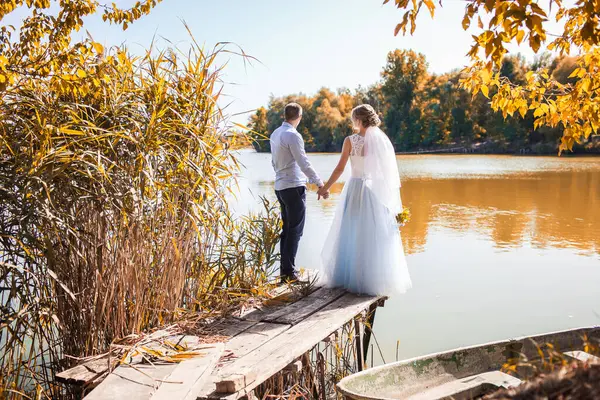 Recém-casados estão na margem de um lago pitoresco — Fotografia de Stock