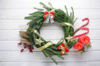 Çam iğneli, mumlu, beyaz ahşap masadaki şekerli el yapımı Noel çelengi..