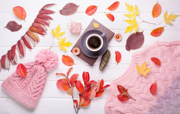 Livro, uma xícara de café e um chapéu de malha quente, em uma mesa branca de madeira do outono — Fotografia de Stock