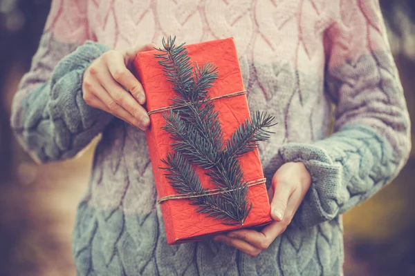 Kobieta gospodarstwa rustykalny ozdobione Boże Narodzenie prezent z gałęzi drzewa — Zdjęcie stockowe
