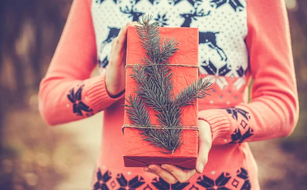 Kobieta gospodarstwa rustykalny ozdobione Boże Narodzenie prezent z gałęzi drzewa — Zdjęcie stockowe