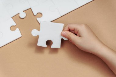 Kahverenginin üzerindeki yapbozun son eksik parçasını bir çocuğun eli yapar. strateji iş konsepti