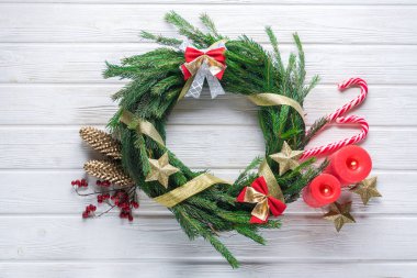 Çam iğneli, mumlu, beyaz ahşap masadaki şekerli el yapımı Noel çelengi..