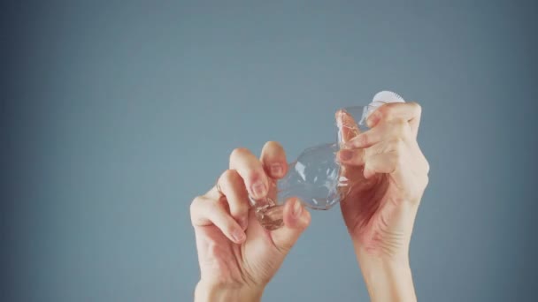 Θηλυκό χέρι συμπιέζει ένα άδειο πλαστικό μπουκάλι — Αρχείο Βίντεο