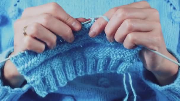 Cerrar las manos de las mujeres tejiendo un suéter de lana azul Imágenes de stock libres de derechos