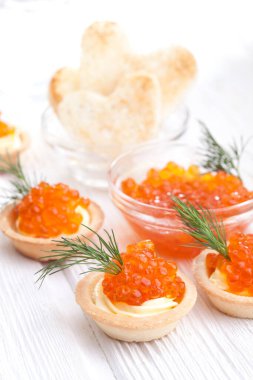 Tereyağlı tartlar ve kırmızı havyar ve beyaz ahşap masayı dereotla kaplayın..