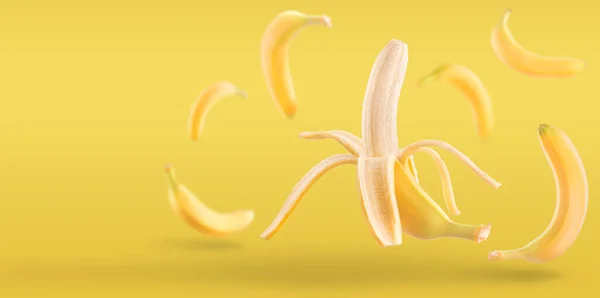 空気中に落ちたバナナの皮をむいた。黄色の背景に隔離されたバナナ。新鮮な果物の浮遊概念. — ストック写真