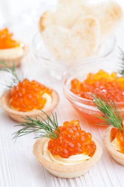 Tereyağlı tartlar ve kırmızı havyar ve beyaz ahşap masayı dereotla kaplayın..