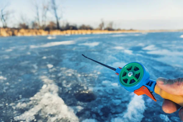 Mano tenendo canna da pesca abbassato in buco in inverno — Foto Stock