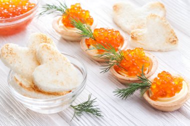 Tereyağlı tartlar ve kırmızı havyar ve beyaz ahşap masayı dereotla kaplayın..