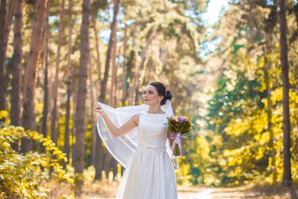 Noiva com um buquê está andando no parque verde — Fotografia de Stock