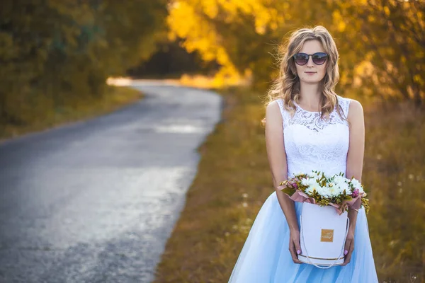 Невеста с букетом гуляет по зеленому парку — стоковое фото