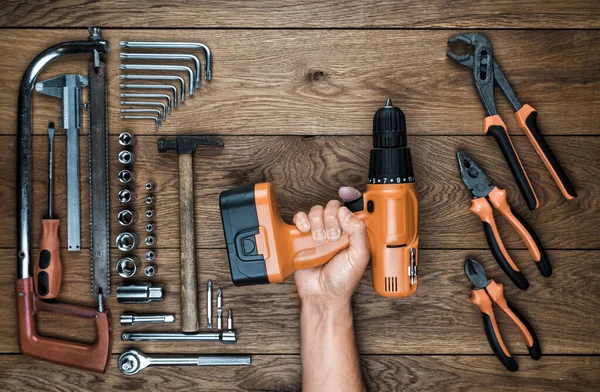 Hand hält Akkuschrauber und Werkzeugkasten auf einem alten Holztisch — Stockfoto