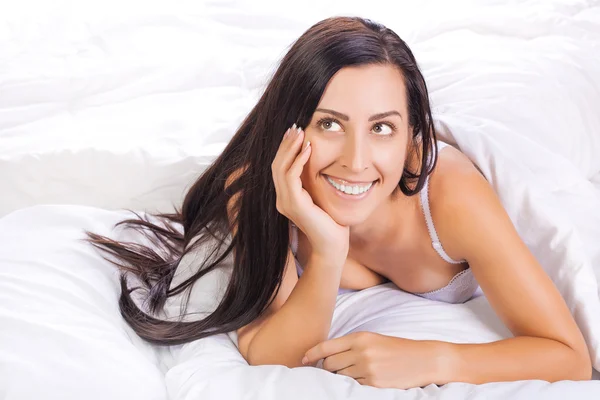 Mujer acostada en la cama y sonriendo — Foto de Stock