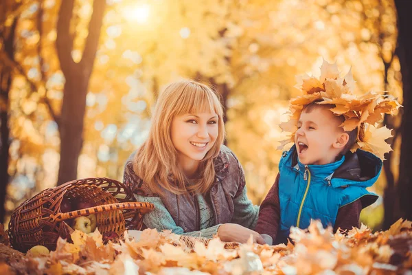 Mother and her kid have fun in the yellow leaves — Stock Photo, Image