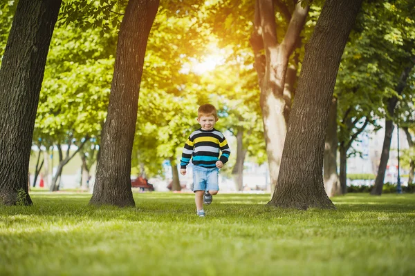 Parktaki çimlerin üzerinde yatan küçük çocuk. — Stok fotoğraf