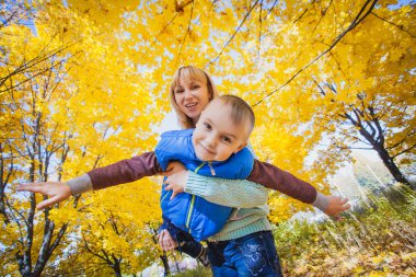 Anne ve çocuğu sarı yapraklarda eğlenin