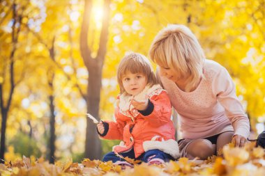Anne ve bebeği sonbahar parkta eğlenin