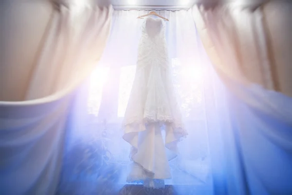 Vestido de noiva branco pendurado em uma janela . — Fotografia de Stock