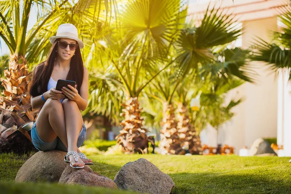Meisje met Tablet PC in de tuin met palm — Stockfoto
