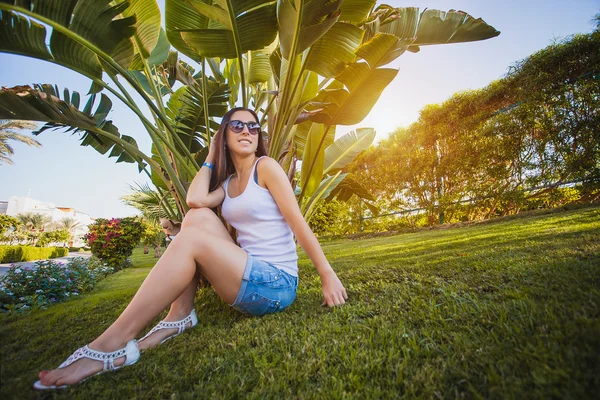 Vrouw is wandelen in de tuin met palmbomen — Stockfoto