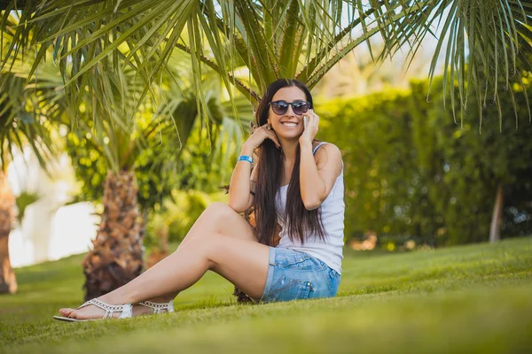 Girl is talking on the phone in the palm garden — Stock Photo, Image