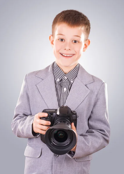 Niño sosteniendo una cámara dslr sobre un fondo azul — Foto de Stock