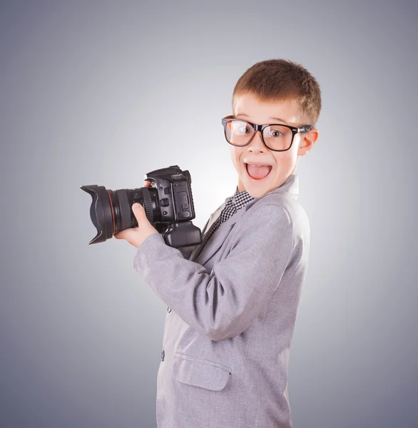 Garoto segurando uma câmera dslr em um fundo azul — Fotografia de Stock