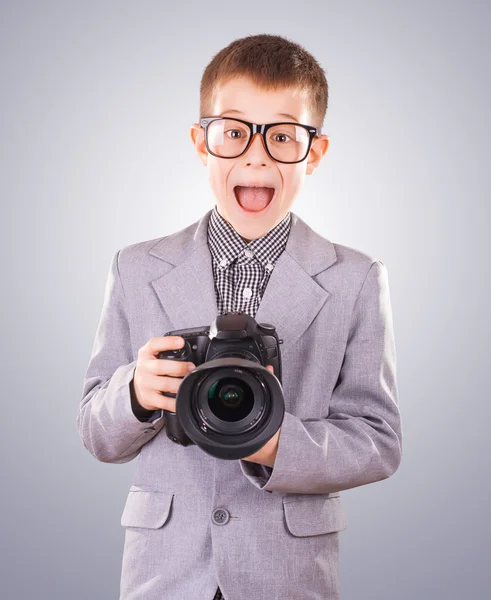 Garoto segurando uma câmera dslr em um fundo azul — Fotografia de Stock