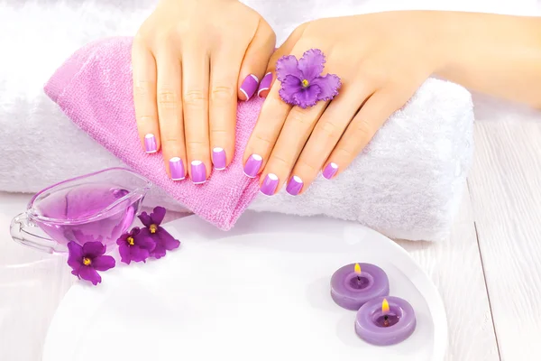 法国修指甲与紫罗兰色的花。水疗中心 — 图库照片