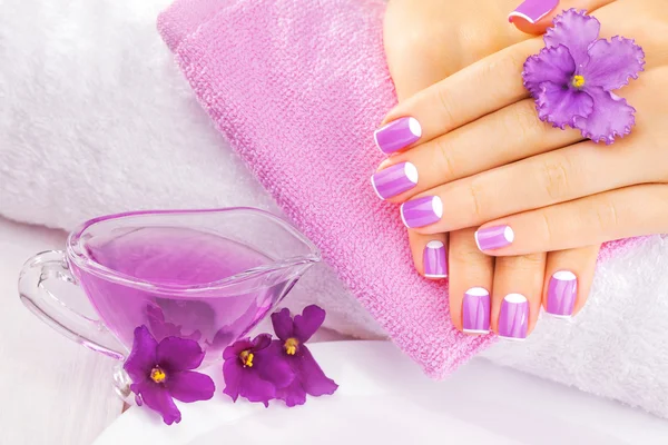 Französische Maniküre mit violetten Blüten. Wellness — Stockfoto