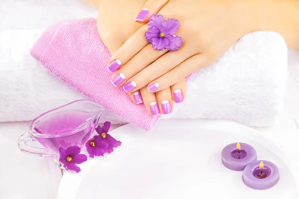 Französische Maniküre mit violetten Blüten. Wellness — Stockfoto