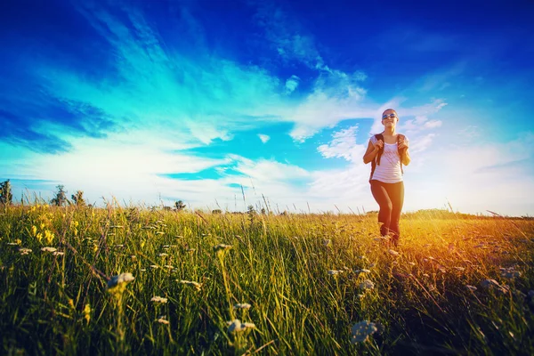 Caminante con mochilas caminando por un prado — Foto de Stock