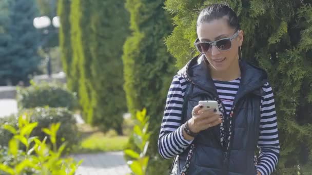 Attraktiv ung kvinna med att prata i mobiltelefon i vacker höst park. Videoklipp