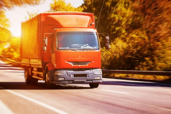 Red truck on blurry asphalt road — Stock Photo, Image