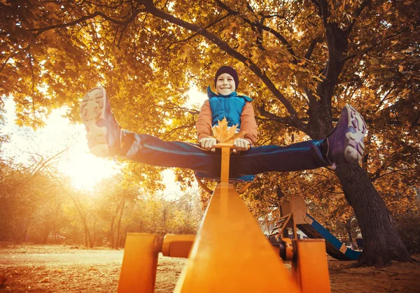 Kid swinging at the park in autumn — Stock Photo, Image