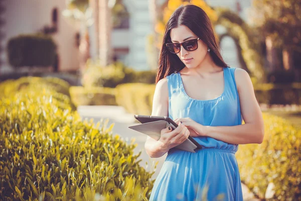 Beautiful woman using tablet in green park — Stock Photo, Image