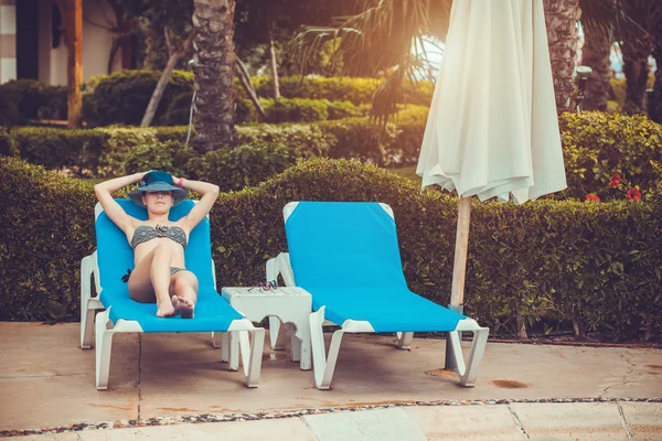 Kvinnan ligger på en solstol vid poolen — Stockfoto