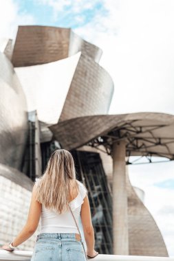 Woman visiting the exterior of the Guggenheim museum in Bilbao, Spain clipart