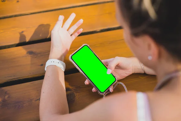緑のクロマキーと木製のテーブルの上に彼女のスマートフォンを使用して女性のモックアップ — ストック写真