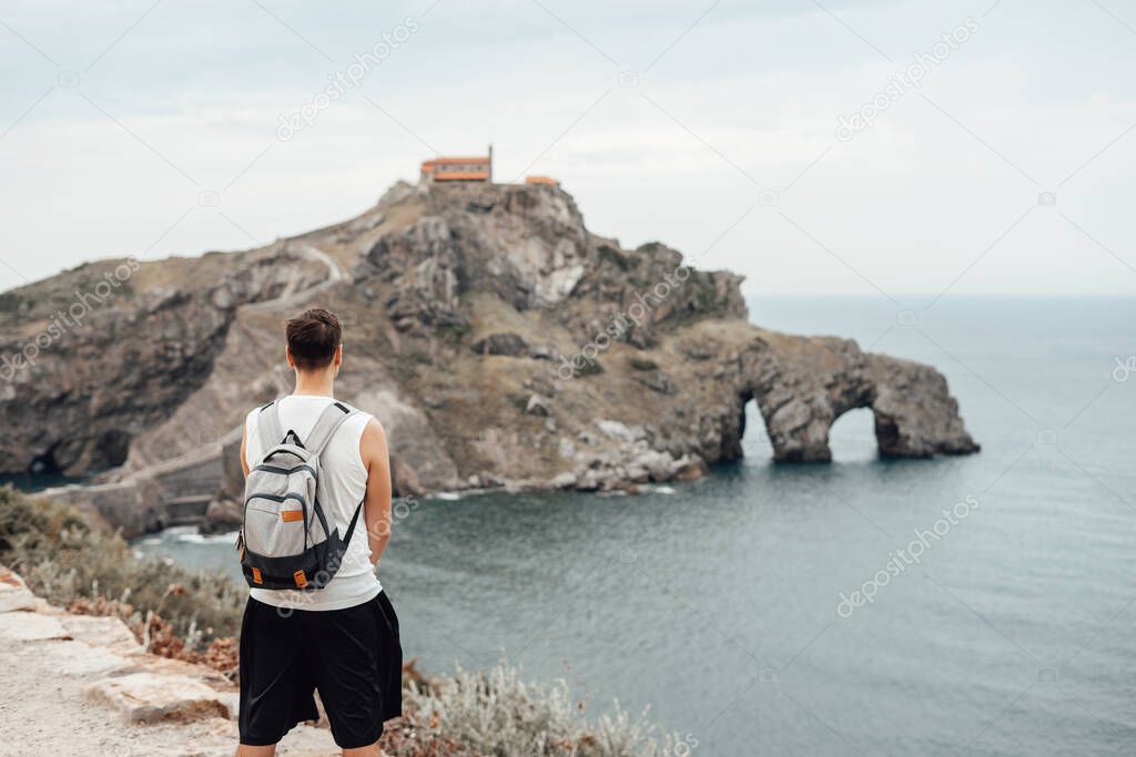 Young man in front of the Gaztelugatxe Island in Vizcaya, Spain