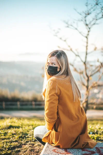 Mujer Abrigo Amarillo Sentada Banco Con Una Mascarilla —  Fotos de Stock