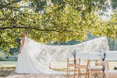 Gelin, bir ağacın altında duvağının keyfini çıkarıyor.