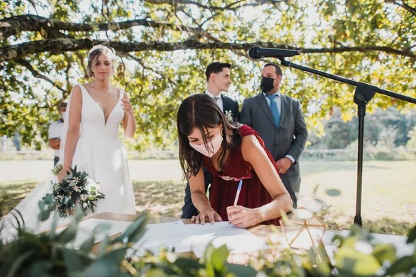 bridesmaid with surgical mask signing legal documents