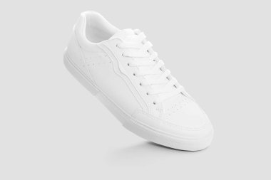 Açık gri bir arkaplan karşısında temel beyaz spor ayakkabıları modeli
