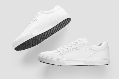 Açık gri bir arkaplan karşısında temel beyaz spor ayakkabıları modeli