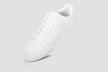 Açık gri bir arkaplan karşısında temel beyaz spor ayakkabıları modeli