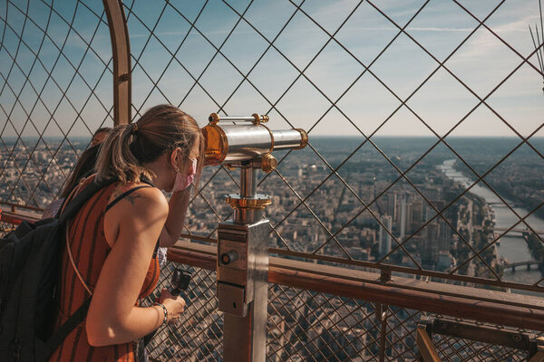 Tourist looking through a telescope on the Eiffel tower in Paris, France